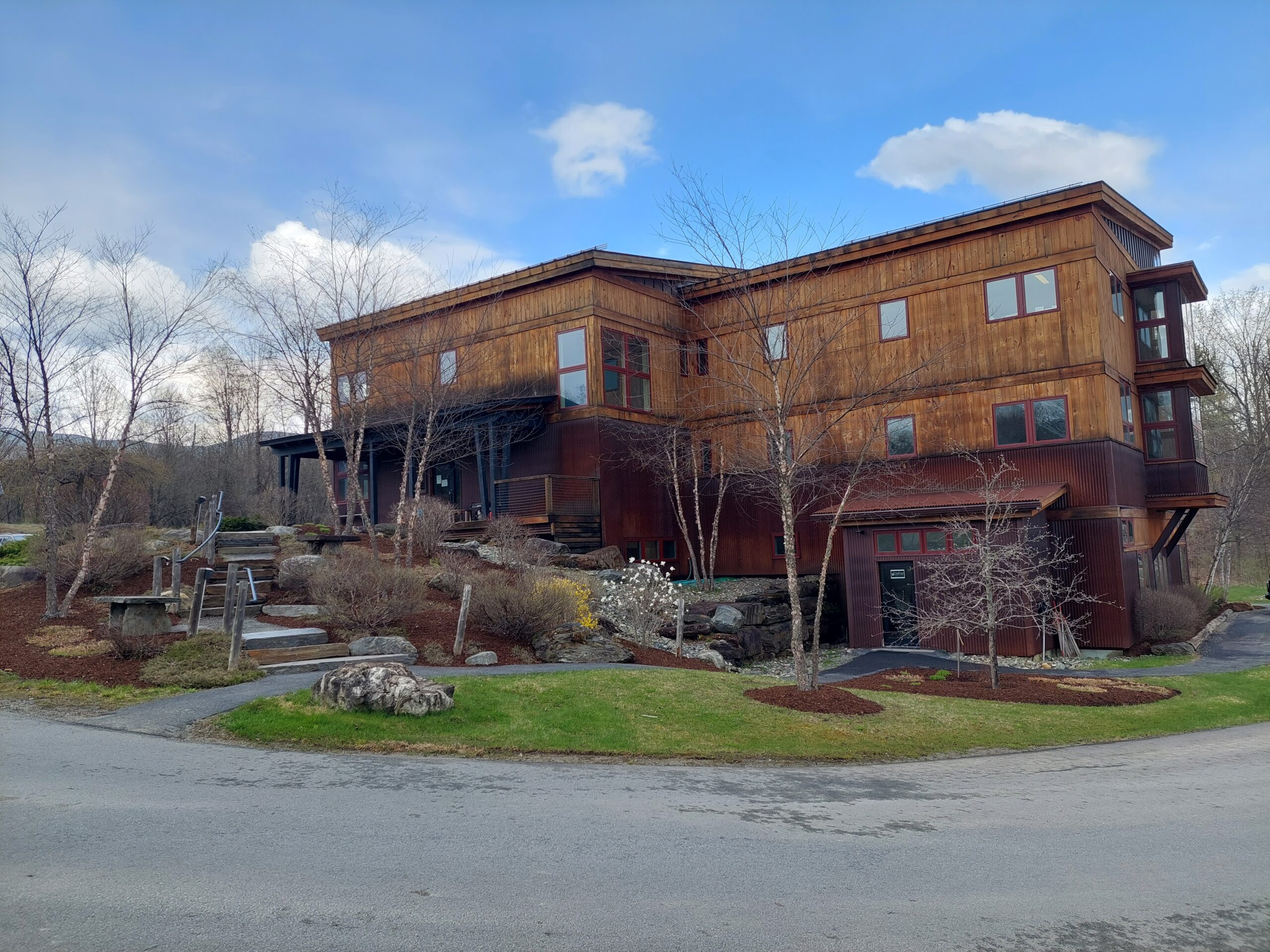 A large building with architectural details sits in an artfully landscaped yard with mountains visible in the distance